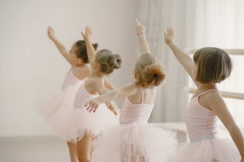 Jonge balletdansers in roze tutu's tijdens de les